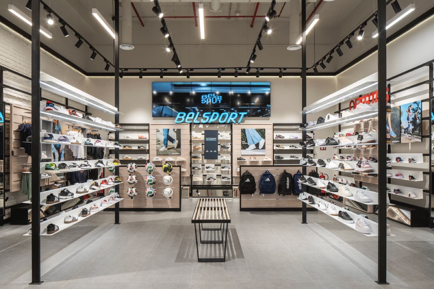 Interior de una tienda Belsport con muros de zapatillas y pantalla digital